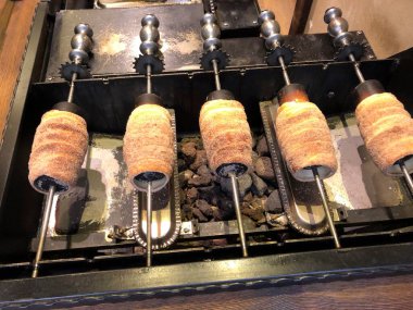 Trdelnk 'i hazırlamak, rulo hamurdan yapılmış, çubuğa sarılmış, sonra da üzerinde şeker ve ceviz karışımı olan bir tür tükürük keki.