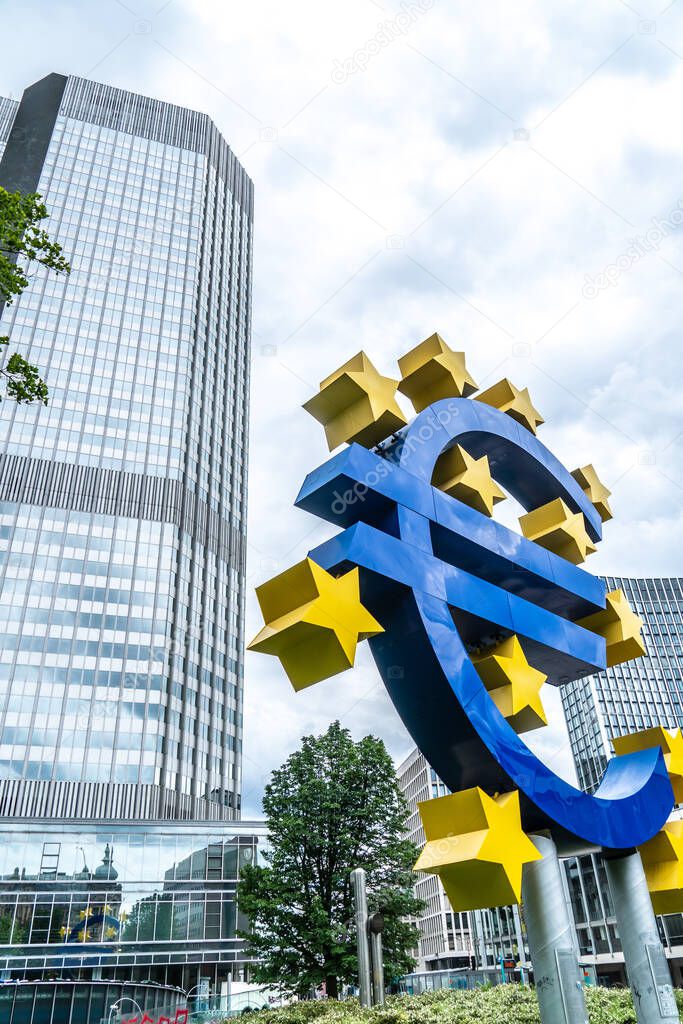 Frankfurt am Main, Germany - June 28, 2020: The Euro-Skulptur (German for Euro sculpture) set up in front of the European Central Bank, electronic signage showing a Euro sign and twelve stars around