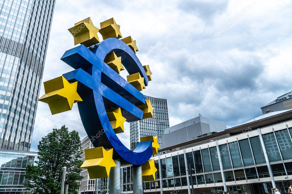 Frankfurt am Main, Germany - June 28, 2020: The Euro-Skulptur (German for Euro sculpture) set up in front of the European Central Bank, electronic signage showing a Euro sign and twelve stars around