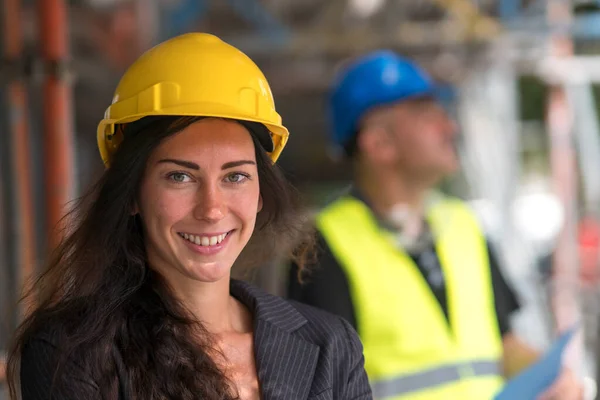 Smiling woman construction engineer, close-up portrait. On background, out of focused construction engineer