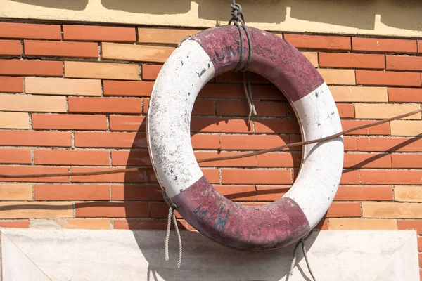 Old ring life buoy, also known as a kisby ring or perry buoy, hanging from a brick wall