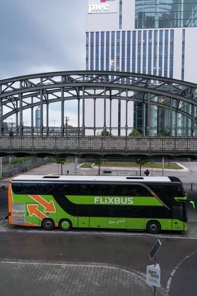 Münih, Almanya - 13 Temmuz 2020: Flixbus yeşil otobüsü PWC işaretli bir binanın yanından geçiyor. Pricewaterhouse Coopers çok uluslu profesyonel hizmet ağıdır.