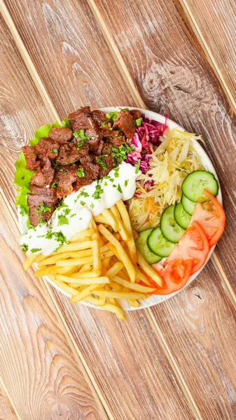 Sığır eti, patates kızartması, sebze ve sos yakın çekim ahşap bir masada shawarma plaka. yukarıdan dikey üst görünüm. Düz yatıyordu