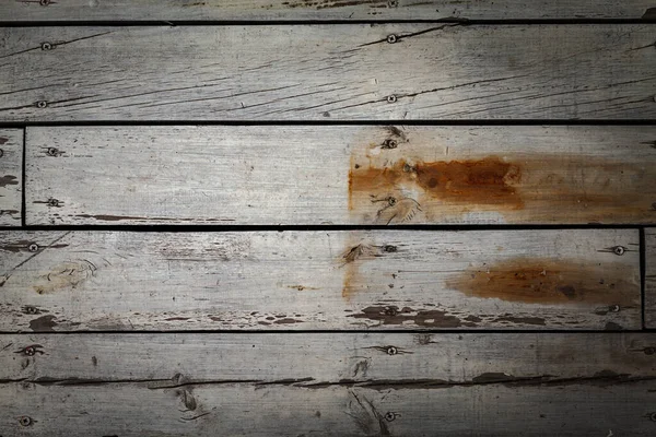 Old wooden wall of boards with weathered and peeled white paint.