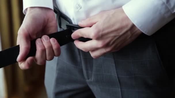 Man tightens the black leather belt on the blue pants, close-up. Man fastens the belt on his trousers, close-up. — Stock Video