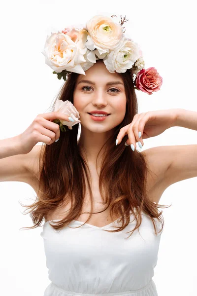 सुंदर तरुण मुलगी हसत आणि पांढरा ड्रेसमध्ये पांढरा पार्श्वभूमीवर फुलांसह पोझिंग. स्टुडिओ चित्र . — स्टॉक फोटो, इमेज