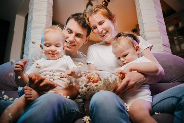 Kanepede patlamış mısır yemek çocuklu genç aile.