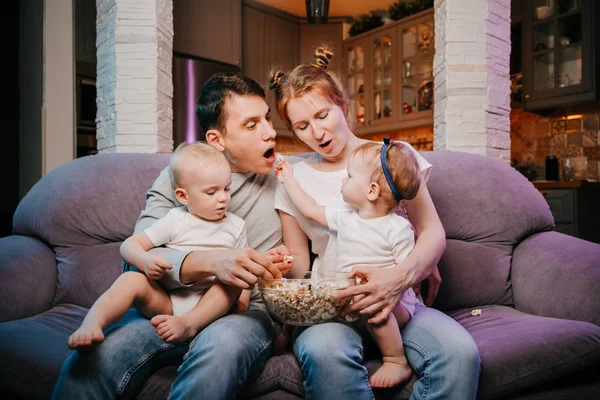 Kanepede patlamış mısır yemek çocuklu genç aile.
