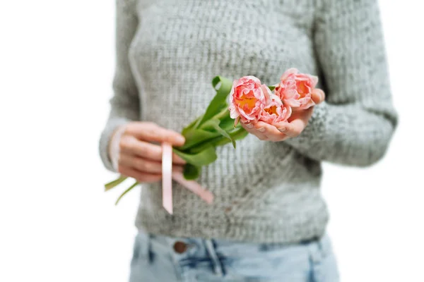 Mujer joven sosteniendo tulipanes rosados sobre un fondo blanco . — Foto de Stock