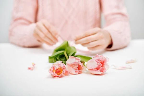 Mujer joven atando una cinta en un ramo de tulipanes rosados . — Foto de Stock