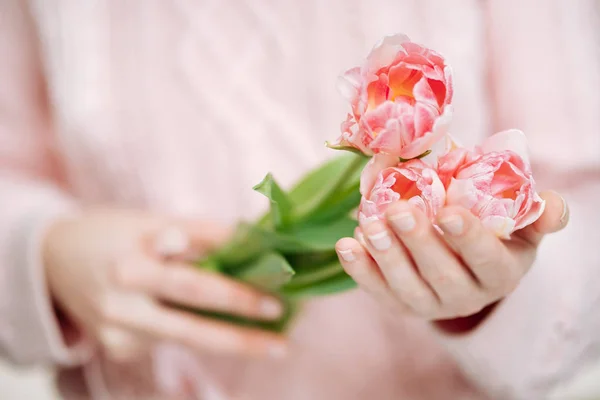 Mujer joven sosteniendo tulipanes rosados sobre un fondo blanco . — Foto de Stock