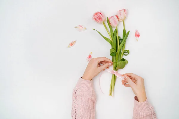 Mujer joven atando una cinta en un ramo de tulipanes rosados . — Foto de Stock