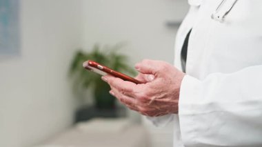 Profesyonel bir doktor sanal tıbbi konsültasyonlar ve verimli dijital sağlık hizmetleri iletişimi için akıllı telefon kullanır. Bu, modern teknolojinin hasta bakımını ve çeşitli sağlık hizmetlerini iyileştirdiğini gösteriyor..