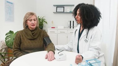 İlgili, farklı bir kadın doktor sakin bir tıbbi muayene sırasında yaşlı bir kadın hastanın kan basıncını ölçer. Bu sağlık, sağlık ve hasta güvenini arttırır..