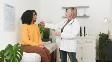 Profesyonel bir kadın doktor, temiz ve modern bir klinikte çeşitli kadın hastalara tıbbi danışmanlık hizmeti sunar. Sağlık uzmanı randevu sırasında empatik bakım, destek ve tavsiye sunar..