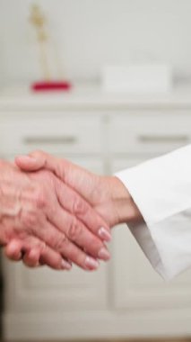 A professional doctor and senior patient exchange a firm handshake, symbolizing trust, understanding, and compassionate health care. This close-up highlights the supportive relationship within a medical setting.