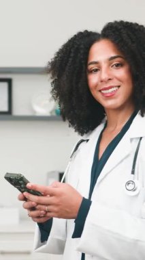 This video features a smiling female doctor confidently using her smartphone in a bright, modern medical setting. It conveys themes of professional healthcare, digital communication, and dedicated patient care.
