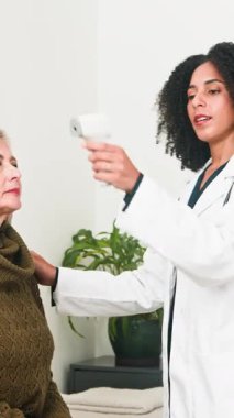 A compassionate medical professional accurately measures an older womans body temperature using a non-contact infrared thermometer. This portrays modern health assessment and patient care.