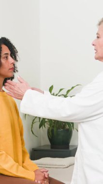 A caring senior doctor meticulously examines a young female patients neck during a routine medical check-up in a clean and bright healthcare setting. Focused on preventative care and well-being.