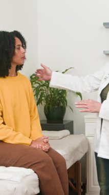 A caring female doctor offers support and guidance to a young woman during a medical examination or therapy session. This compassionate interaction highlights patient-centered care and well-being in a professional health clinic.