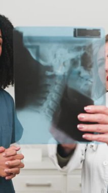 Two dedicated female medical professionals intensely examine an X-ray film, collaborating on a patients diagnosis. Their focused discussion ensures precise healthcare planning and effective treatment solutions in a modern clinic setting.