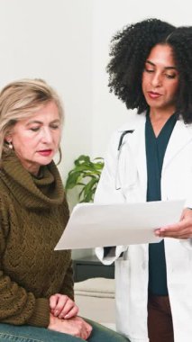 A compassionate female doctor discusses health information with her older female patient during a medical consultation. She provides empathetic care and support, highlighting patient-doctor communication.