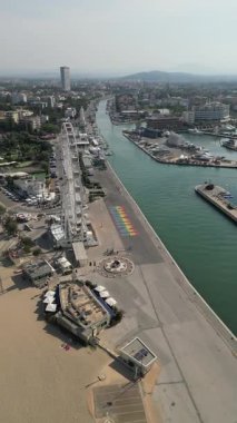 Geriye doğru uçan hava görüntüsü İtalya 'nın rimini şehrini gözler önüne seriyor. Limandaki kanalı, sahili ve dönme dolabı gösteren güzel bir deniz manzarası.