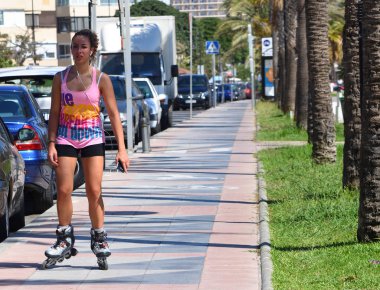 Torremolinos, Endülüs, İspanya - 24 Eylül 2018: Kaldırım boyunca çekici genç kadın paten.