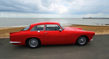 FELIXSTOWE, SUFFOLK, ENGLAND - MAYIS 05, 2019: Arka planda deniz ve plaj ile deniz kenarına park edilmiş klasik Kırmızı Eşsiz GT Motorlu Araç.