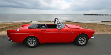 FELIXSTOWE, SUFFOLK, ENGLAND - MAYIS 05, 2019: Klasik Red Sunbeam Tiger Üstü açılabilen Arabası plaj ve deniz manzaralı deniz gezintisi.