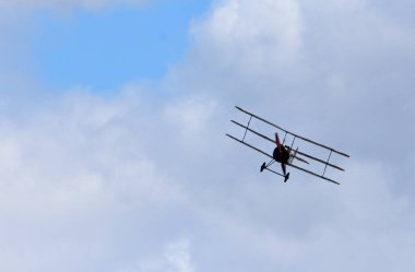 Klasik Sopwith Triplane bulutlar ve mavi gökyüzü ile uçuyor.