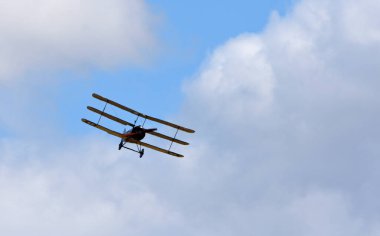  Klasik Sopwith Triplane bulutlar ve mavi gökyüzü ile uçuyor.
