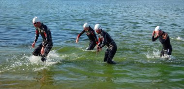GRAFHAM, CAMBRIDGESHIRE, İngiltere - 06 AĞUSTOS 2017: Önde gelen yarışmacılar yüzmenin sonunda sudan çıkıyorlar.