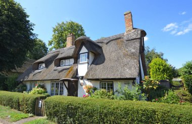 Houghton, Cambridgeshire, England -  August 08, 2025: Thatched Cottage with hedge Houghton Cambridgeshire