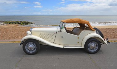Felixstowe, Suffolk, England - May 04, 2025: Classic MG TD with fabric roof on parked on seafront promenade beach and sea in background