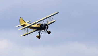 Little Gransden, Cambridgeshire, İngiltere - 24 Ağustos 2025: Vintage Waco UPF-7 çift kanatlı uçaklar bulutlara karşı uçuyor.