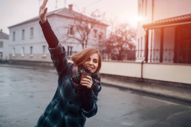 Genç, yetişkin bir kadın, elinde bir fincan kahveyle şehirde kalıyor. 