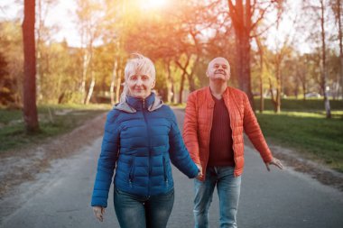 mutlu yaşlılar çift tutun el ve yürüyüş;