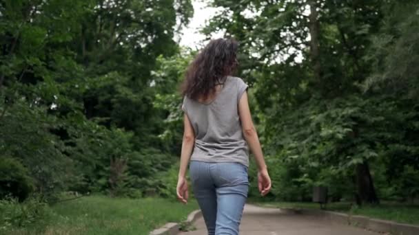 Fiatal gyönyörű göndör barna nő mosolyog és séta — Stock videók