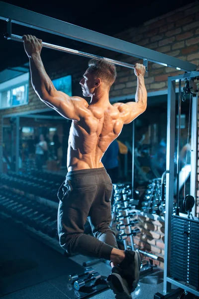 Jonge bodybuilder met perfect lichaam optrekken met gym bar — Stockfoto