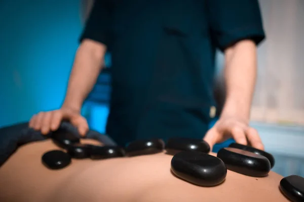 Massagista fazendo cura massagem de pedra para as mulheres coluna vertebral — Fotografia de Stock