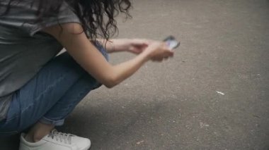 Kadın yerden kırık telefonu kaldırıyor. 