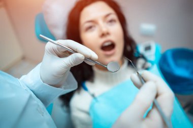 Güzel esmer kıvırcık kadın dişçi modern klinikteki hastayı tedavi ediyor.