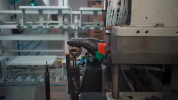 Человек работает с автоматическим оборудованием на обувной фабрике — стоковое видео