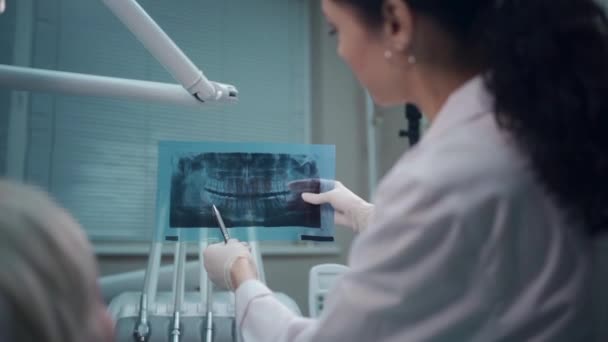 Dentiste professionnel femme montrer panoramique bouche X-ray image au patient — Video