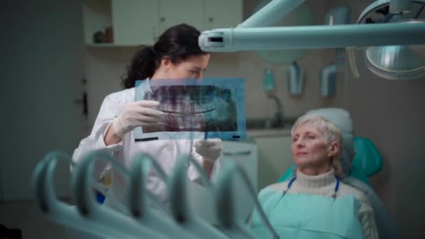 Profissional dentista feminino mostrar imagem de raios-x da boca panorâmica para o paciente — Vídeo de Stock