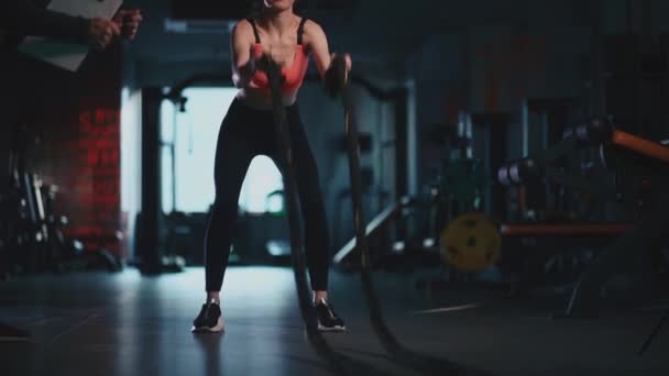 Atlético feminino exercitando cordas no moderno ginásio com personal trainer — Vídeo de Stock