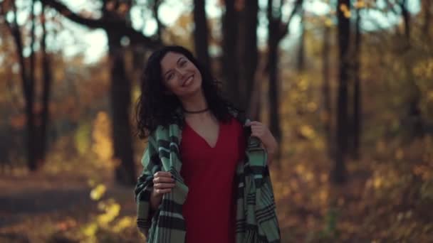 Vacker lockig brunett kvinnlig promenad i höstparken och leende — Stockvideo