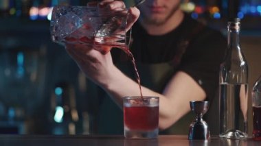 Barmen klasik negroni kokteylini rom ve buzla karıştırıyor.
