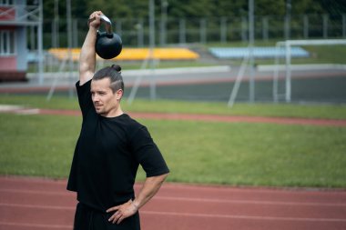 Genç atlet spor yapıyor ve kettlebell ile spor egzersizleri yapıyor.